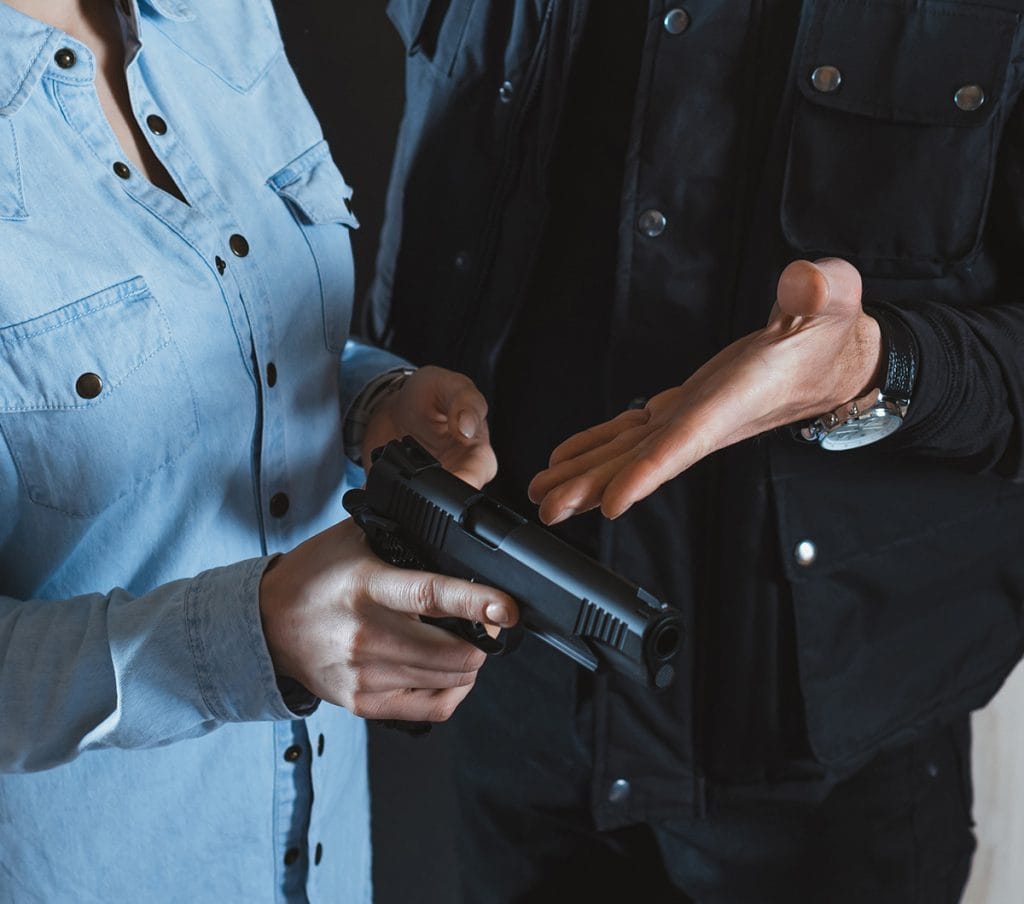A firearm instructor demonstrating safe handgun handling and inspection procedures during a gun safety training session.