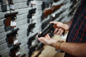 A Man holds a handgun in a gun shop.