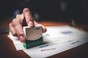 close up of paperwork being approved with a stamp